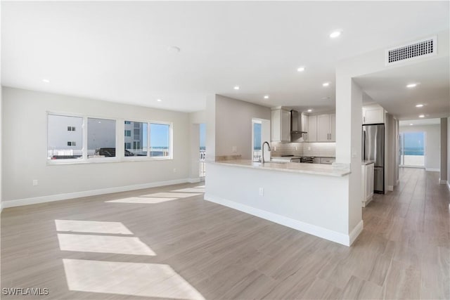 25900 Hickory Blvd Unit 101, Bonita Springs, FL 34134 - kitchen featuring freestanding refrigerator, visible vents, light wood finished floors, and wall chimney range hood