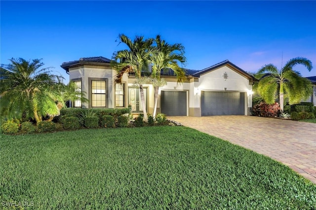 mediterranean / spanish home with stucco siding, an attached garage, driveway, and a front yard