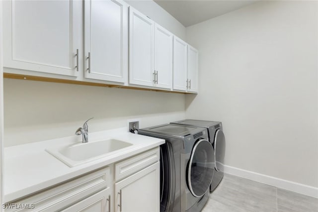 clothes washing area featuring cabinet space, baseboards, washer and dryer, and a sink