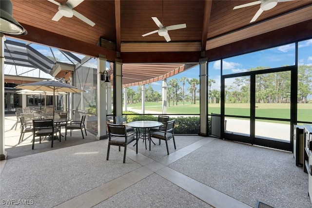 sunroom featuring a ceiling fan, outdoor dining space, and view of golf course
