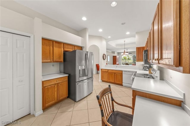 6683 Castlelawn Pl, Naples, FL 34113 - kitchen featuring brown cabinets, a tray ceiling, light tile patterned floors, and stainless steel appliances
