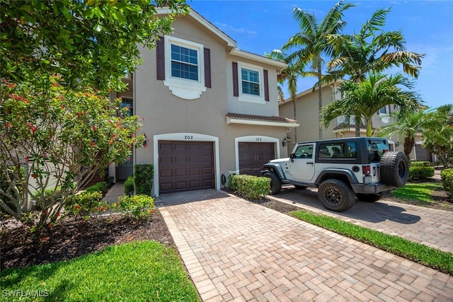 6532 Monterey Pt Unit 202, Naples, FL 34105 - view of front of property featuring an attached garage, decorative driveway, stucco siding, and a tile roof