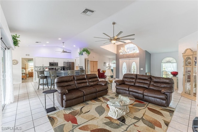 living area with light tile patterned floors, ceiling fan with notable chandelier, lofted ceiling, and visible vents