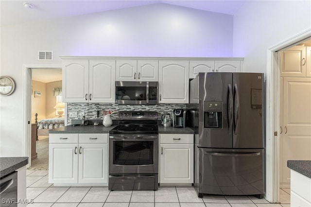 kitchen with visible vents, stainless steel appliances, dark countertops, vaulted ceiling, and backsplash