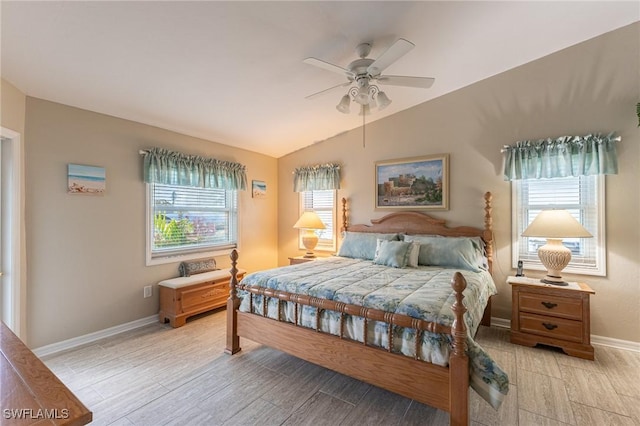 bedroom featuring baseboards, vaulted ceiling, multiple windows, and light wood-type flooring