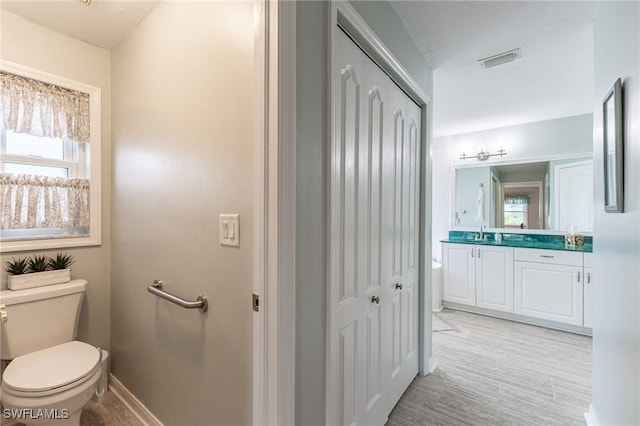 bathroom featuring vanity, toilet, baseboards, visible vents, and wood finished floors
