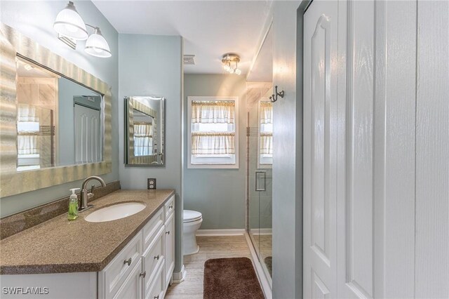 full bath with baseboards, toilet, a stall shower, and vanity