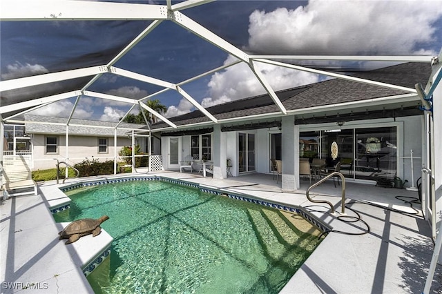 outdoor pool featuring glass enclosure and a patio area