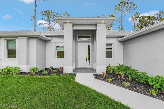1606 Euclid Ave, Lehigh Acres, FL 33972 - entrance to property with roof with shingles, a lawn, and stucco siding