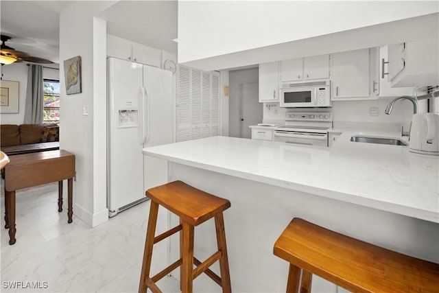 kitchen with ceiling fan, white appliances, a peninsula, marble finish floor, and a sink
