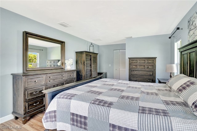 bedroom with visible vents, light wood-type flooring, a closet, and multiple windows