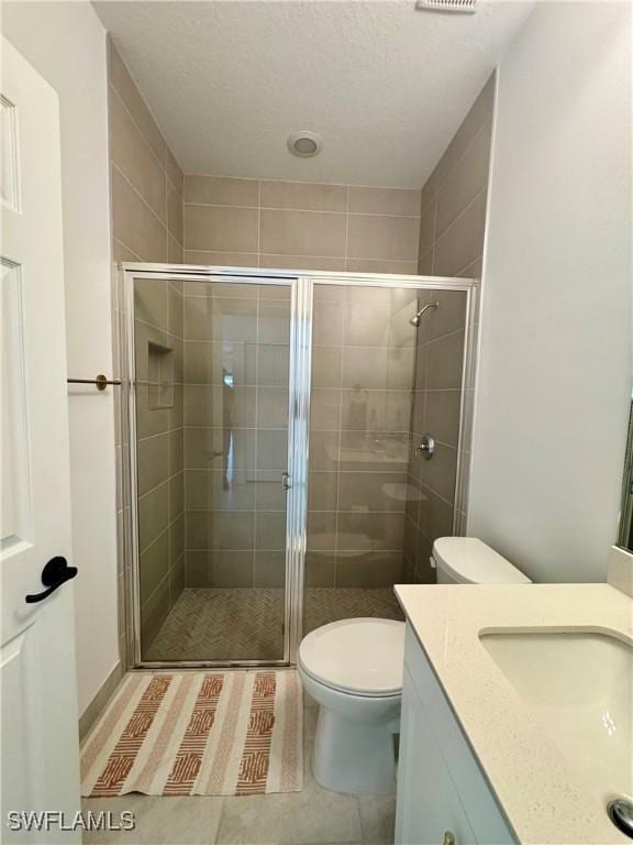 full bath featuring toilet, vanity, a stall shower, and tile patterned flooring