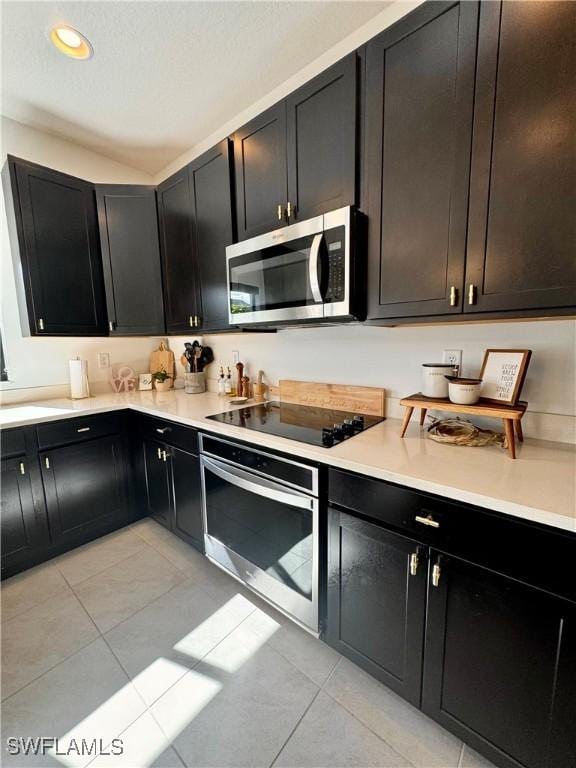 kitchen featuring light countertops, recessed lighting, appliances with stainless steel finishes, dark cabinets, and light tile patterned floors