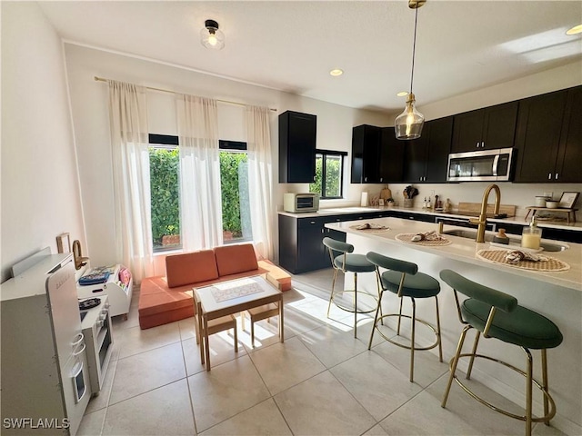 kitchen with stainless steel microwave, light countertops, dark cabinetry, and a breakfast bar area