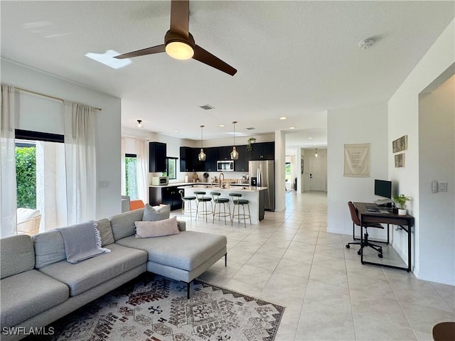 living room featuring light tile patterned flooring, baseboards, visible vents, and a ceiling fan