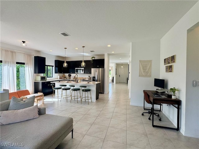 living room with baseboards, a textured ceiling, visible vents, and light tile patterned floors