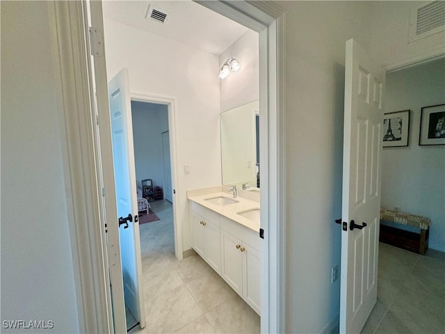 ensuite bathroom with double vanity, a sink, ensuite bath, and visible vents