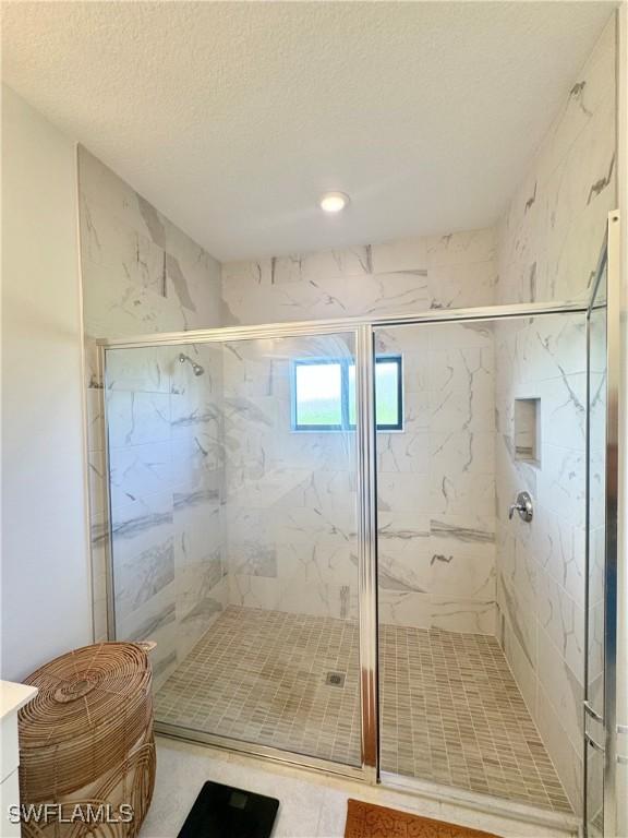 full bath with a textured ceiling and a marble finish shower