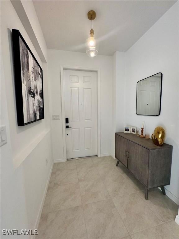 interior space with baseboards, ceiling fan, and light tile patterned flooring