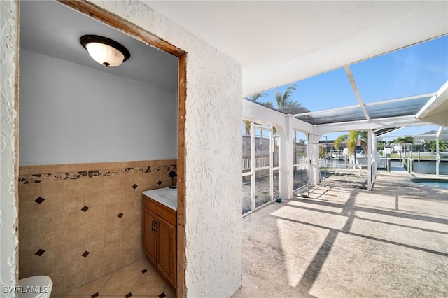 interior space featuring a healthy amount of sunlight, tile walls, wainscoting, and vanity