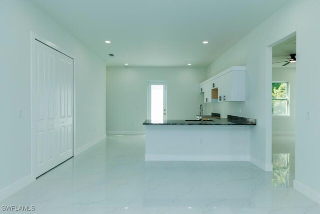 kitchen featuring a peninsula, white cabinets, recessed lighting, marble finish floor, and baseboards