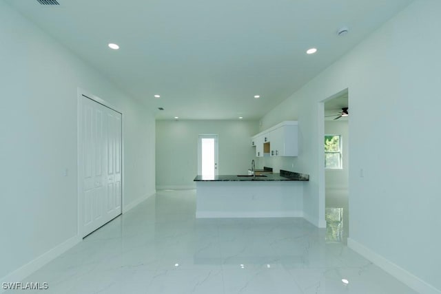 kitchen featuring white cabinets, recessed lighting, a sink, dark countertops, and baseboards