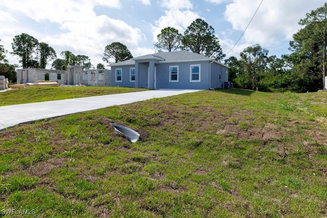 ranch-style house featuring concrete driveway, stucco siding, a front lawn, and central AC