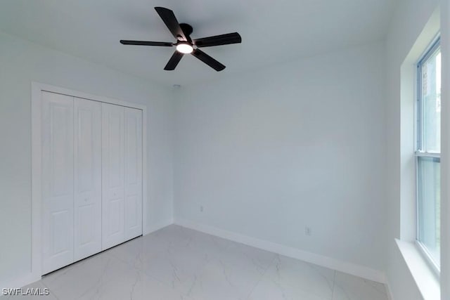 empty room with baseboards, a ceiling fan, and marble finish floor