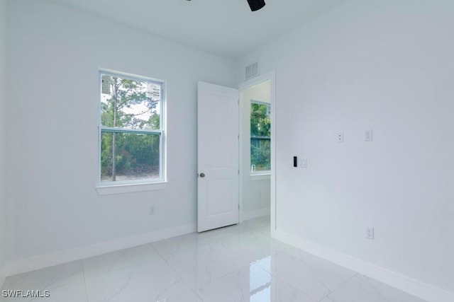 empty room featuring ceiling fan, marble finish floor, baseboards, and visible vents