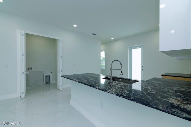 kitchen with baseboards, dark stone countertops, recessed lighting, marble finish floor, and a sink