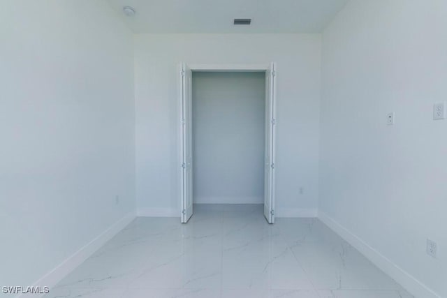 empty room featuring marble finish floor, baseboards, and visible vents