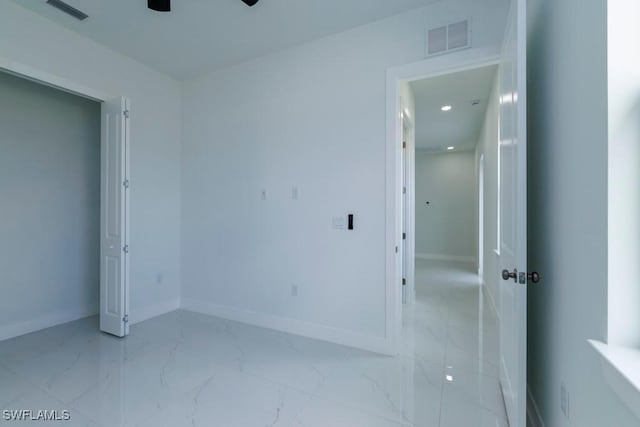 unfurnished bedroom featuring ceiling fan, marble finish floor, baseboards, and visible vents