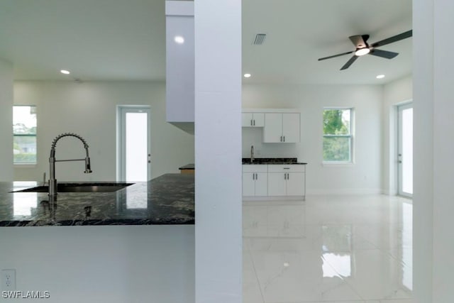 kitchen with dark stone counters, white cabinetry, recessed lighting, marble finish floor, and a sink