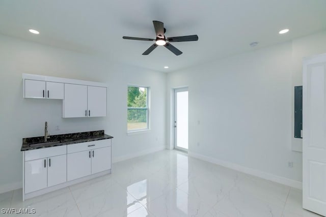 kitchen with white cabinets, marble finish floor, baseboards, and a ceiling fan