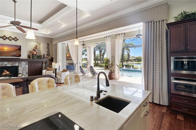 kitchen with open floor plan, crown molding, oven, ceiling fan, and a sink