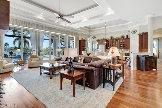 living room with recessed lighting, a ceiling fan, crown molding, a tray ceiling, and light wood finished floors