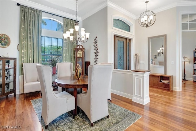 dining area with a notable chandelier, baseboards, crown molding, and light wood-style flooring