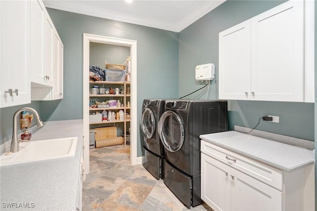 clothes washing area with crown molding, cabinet space, stone finish floor, a sink, and washing machine and dryer