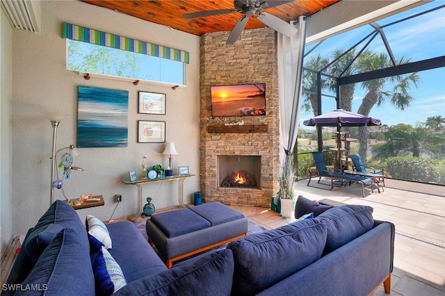 living room featuring a ceiling fan, an outdoor stone fireplace, a towering ceiling, and wood ceiling