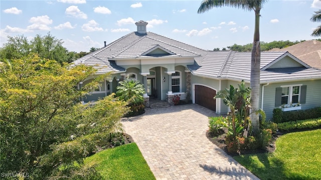 mediterranean / spanish home featuring a tiled roof, an attached garage, and decorative driveway