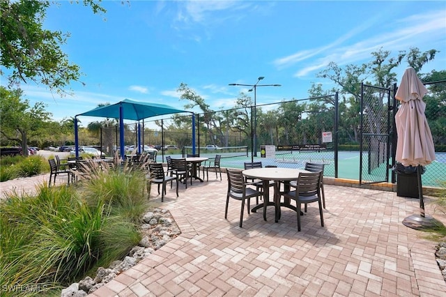 view of patio with a tennis court and fence