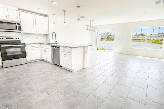 15051 Caspian Tern Ct Unit 106, North Fort Myers, FL 33917 - kitchen featuring appliances with stainless steel finishes, a sink, backsplash, a peninsula, and open floor plan