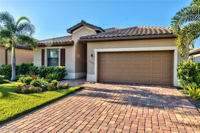 view of front of house featuring a tiled roof, a garage, decorative driveway, and stucco siding