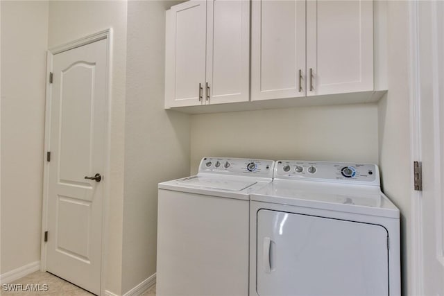 laundry area featuring baseboards, washing machine and dryer, and cabinet space