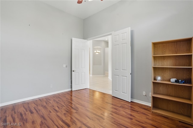 510 13th St NW, Naples, FL 34120 - unfurnished bedroom featuring arched walkways, baseboards, wood finished floors, and a ceiling fan