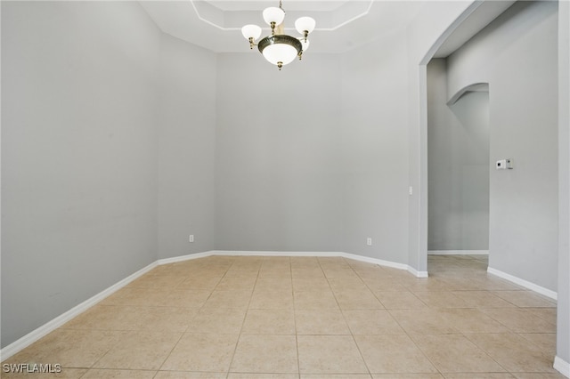 510 13th St NW, Naples, FL 34120 - unfurnished room with a chandelier, a raised ceiling, light tile patterned floors, baseboards, and arched walkways
