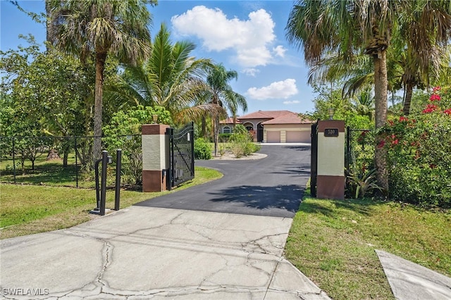 510 13th St NW, Naples, FL 34120 - view of front facade featuring stucco siding, aphalt driveway, a gate, a front lawn, and a garage