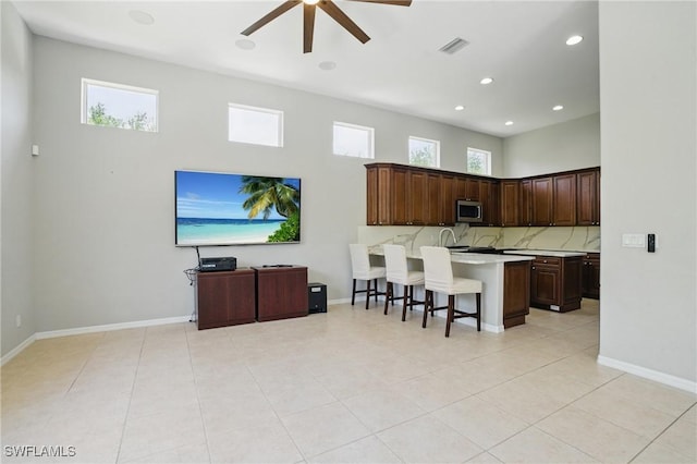 510 13th St NW, Naples, FL 34120 - kitchen with light countertops, stainless steel microwave, a breakfast bar, ceiling fan, and visible vents