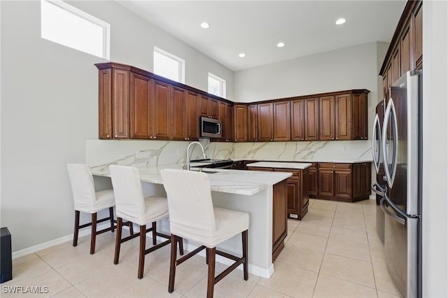 510 13th St NW, Naples, FL 34120 - kitchen with a peninsula, appliances with stainless steel finishes, a sink, backsplash, and light tile patterned floors