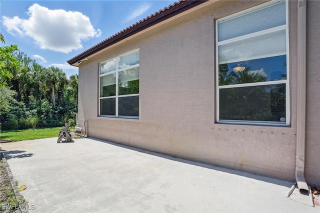 510 13th St NW, Naples, FL 34120 - view of home's exterior featuring a patio, a tiled roof, and stucco siding